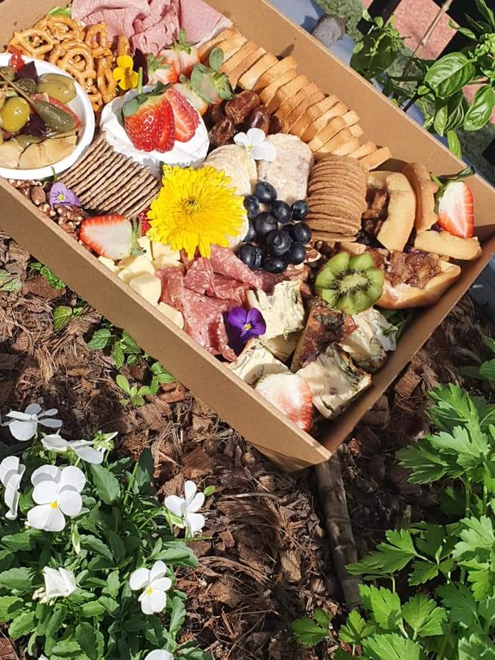 Grazing box with cheeses, cured meats, strawberries, blueberries, crackers and edible flowers