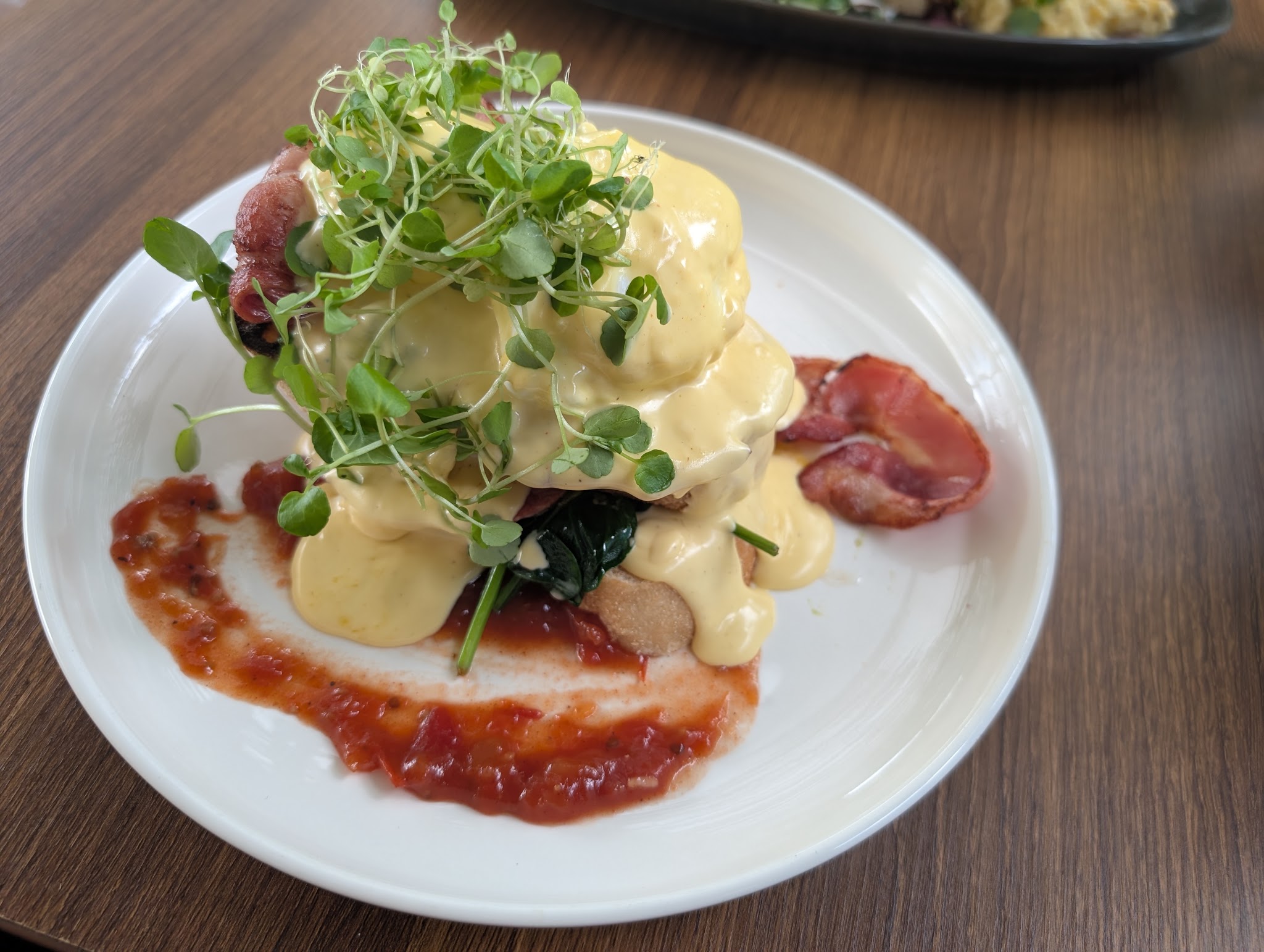 Eggs benedict with bacon, spinach, hollandaise and microgreens