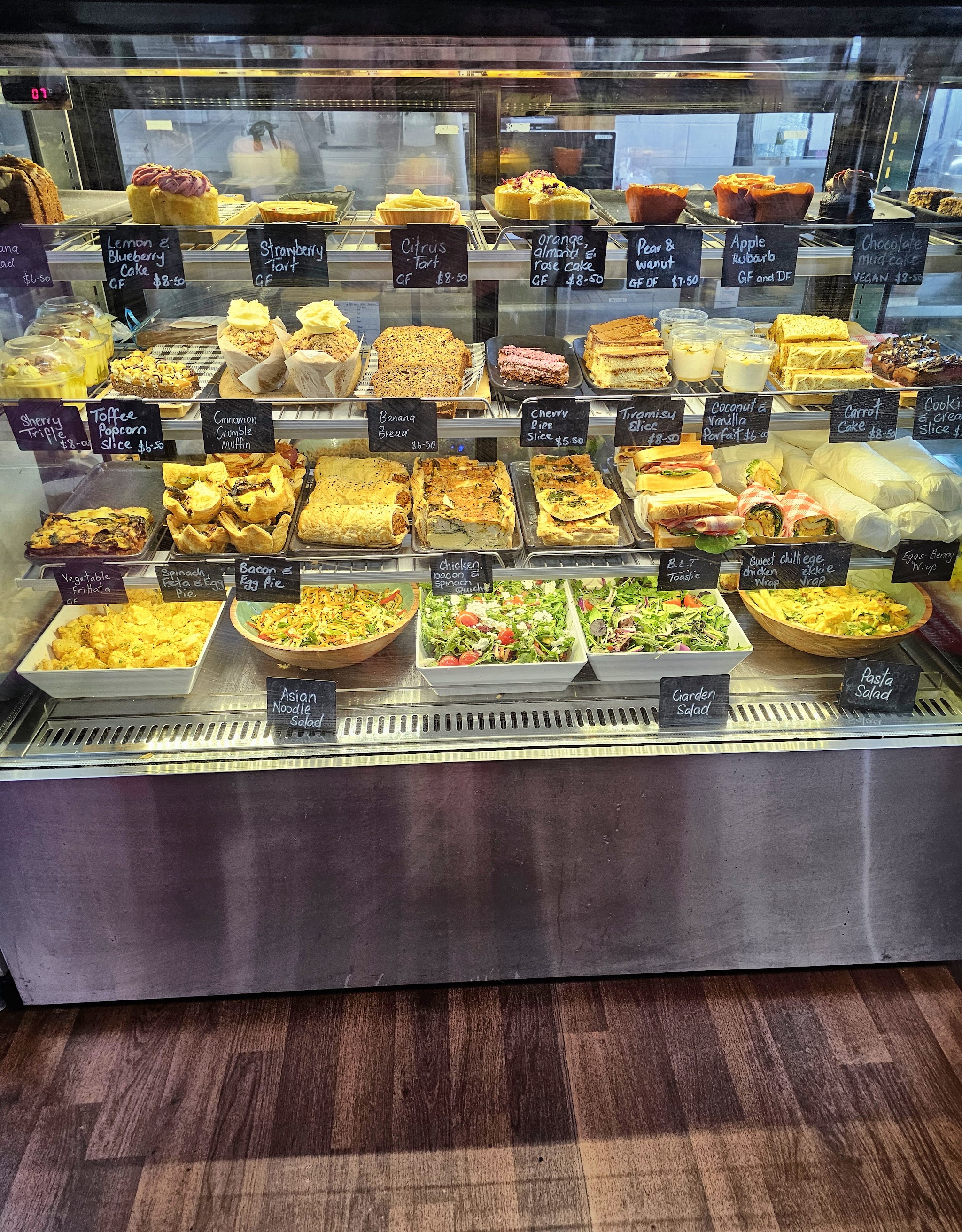 The Coffee Patch cake cabinet with handwritten chalkboard labels for cakes, pies, wraps and salads