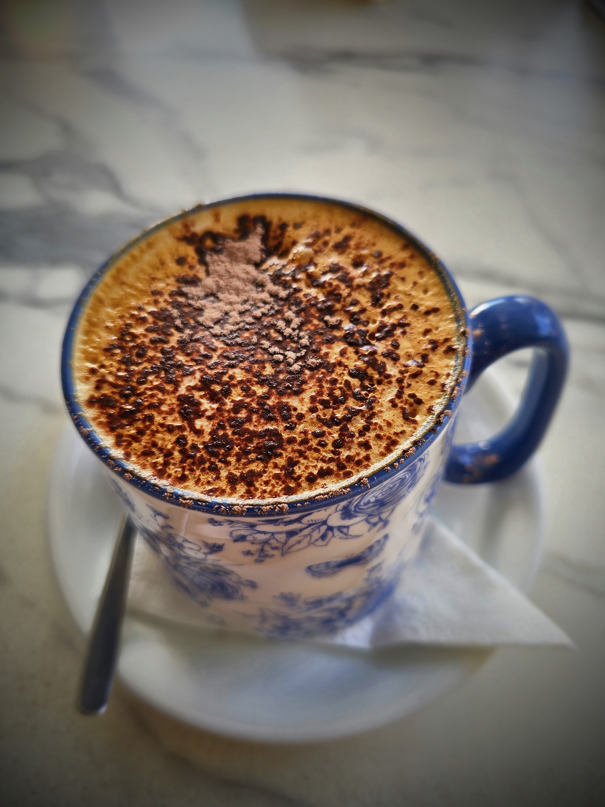 Chocolate-dusted coffee in a blue and white floral mug